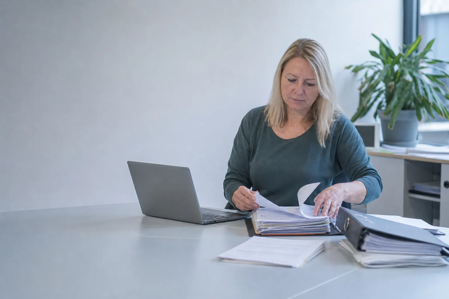 Mitarbeiterin ordnet Teilnehmerunterlagen und Anwesenheitslisten an einem Schreibtisch
